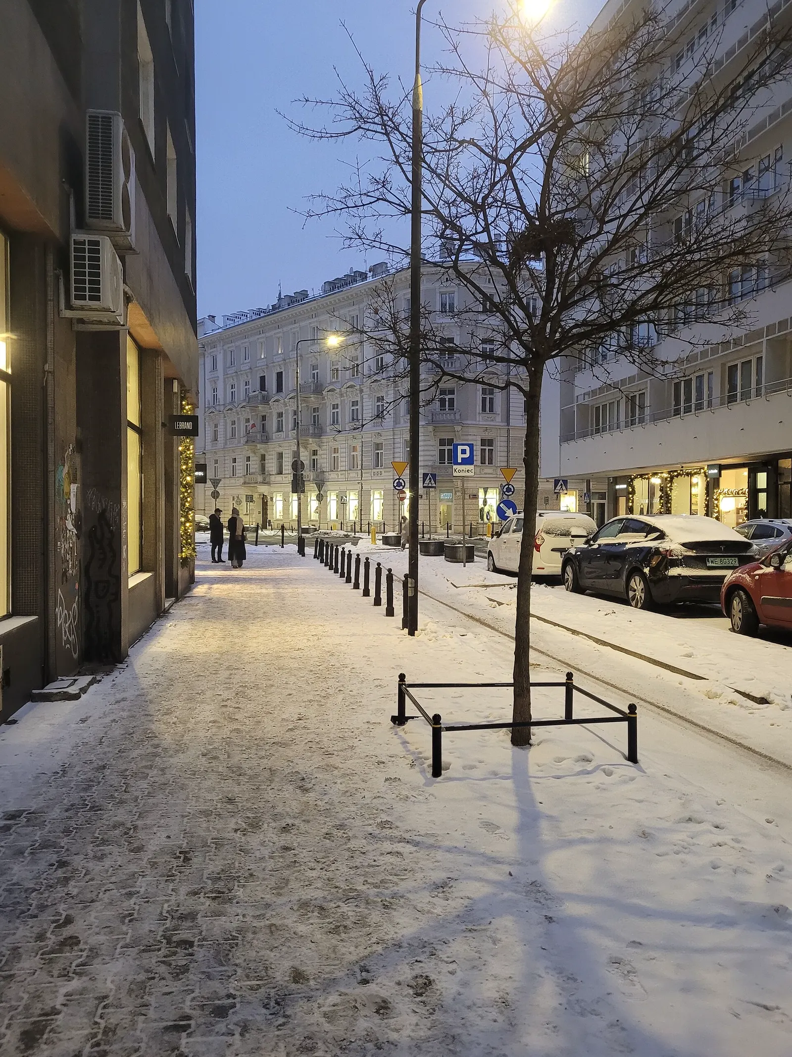 Calle Koszykowa de Varsovia con nieve al anochecer y faroles encendidos